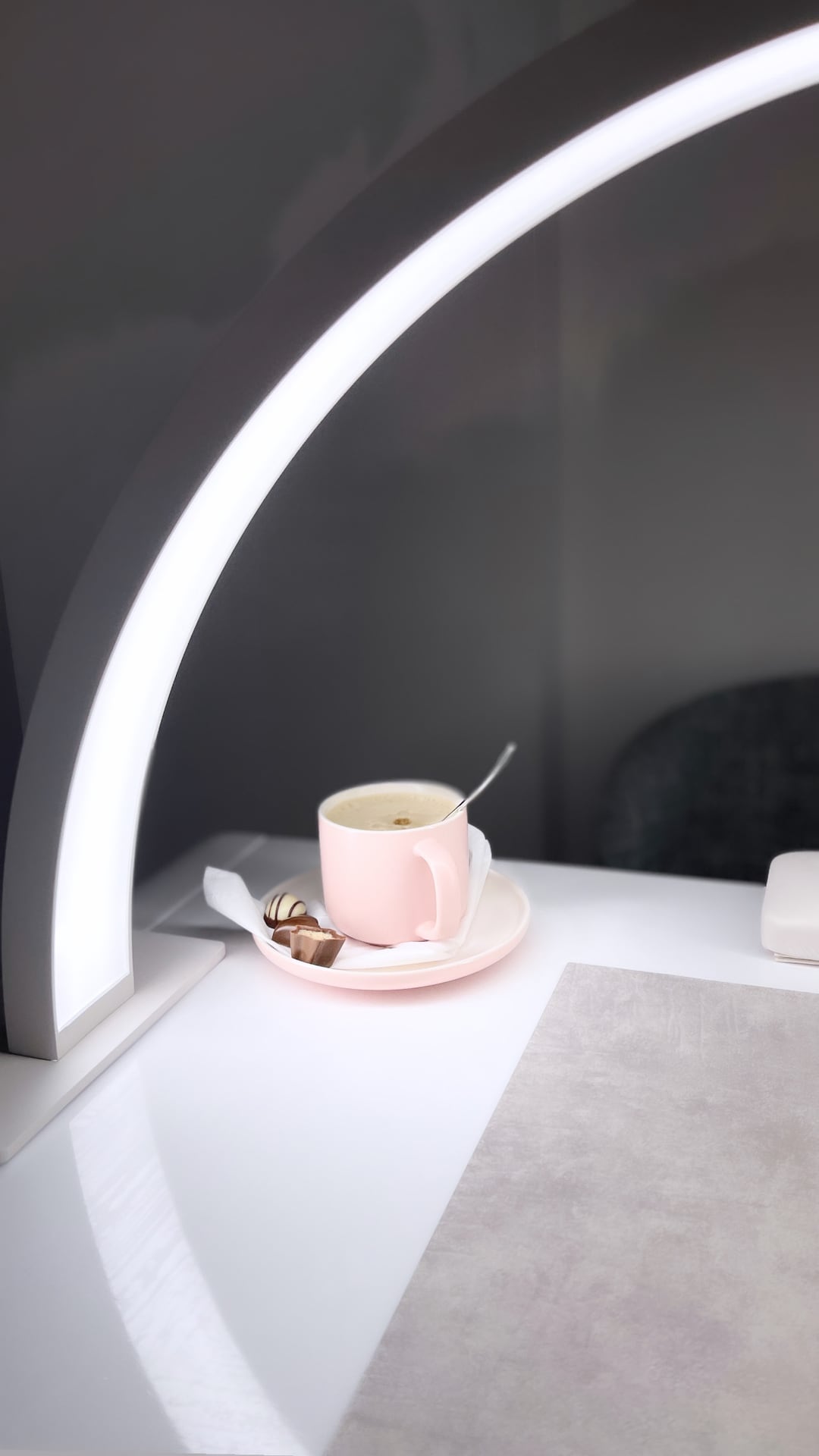 Kaffee und Praline am Arbeitsplatz unter Bogenlampe